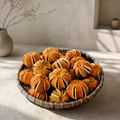 Whole dried orange pomanders with vertical hand-cut slits, showcasing a deep amber citrus interior and rustic  texture.